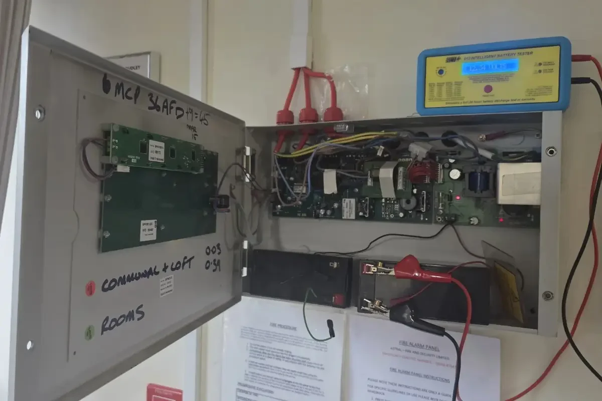 Engineer performing fire alarm system maintenance and inspection in commercial building
